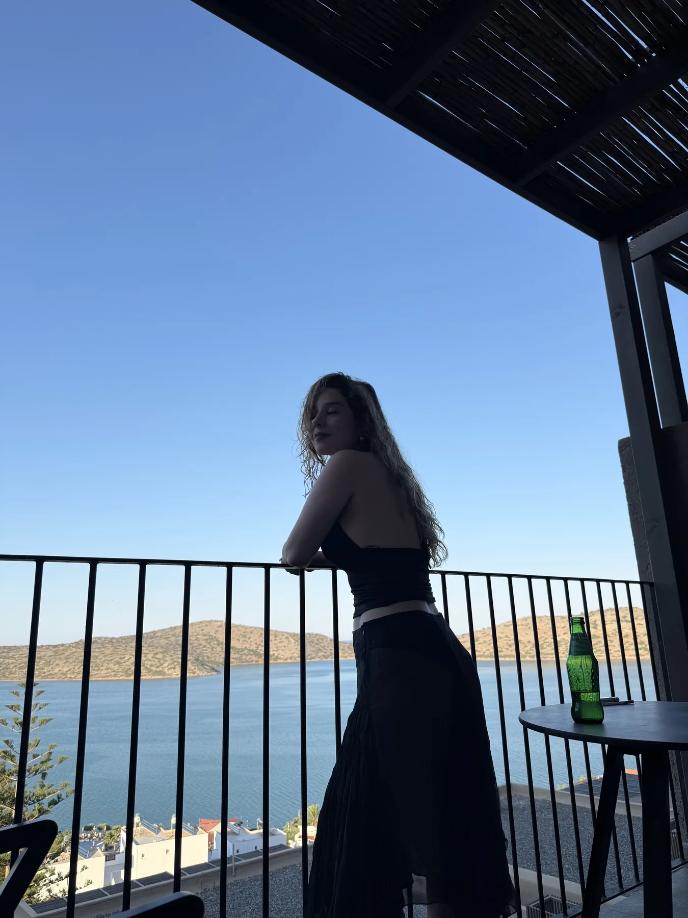 Isilsu standing on a balcony above a quiet bay
